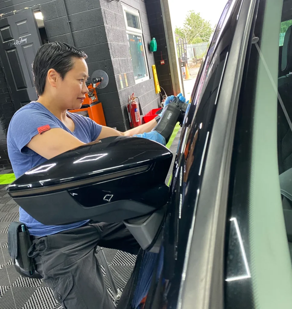Soo from Hydrowax using a machine polisher on a black car door panel to remove swirl marks